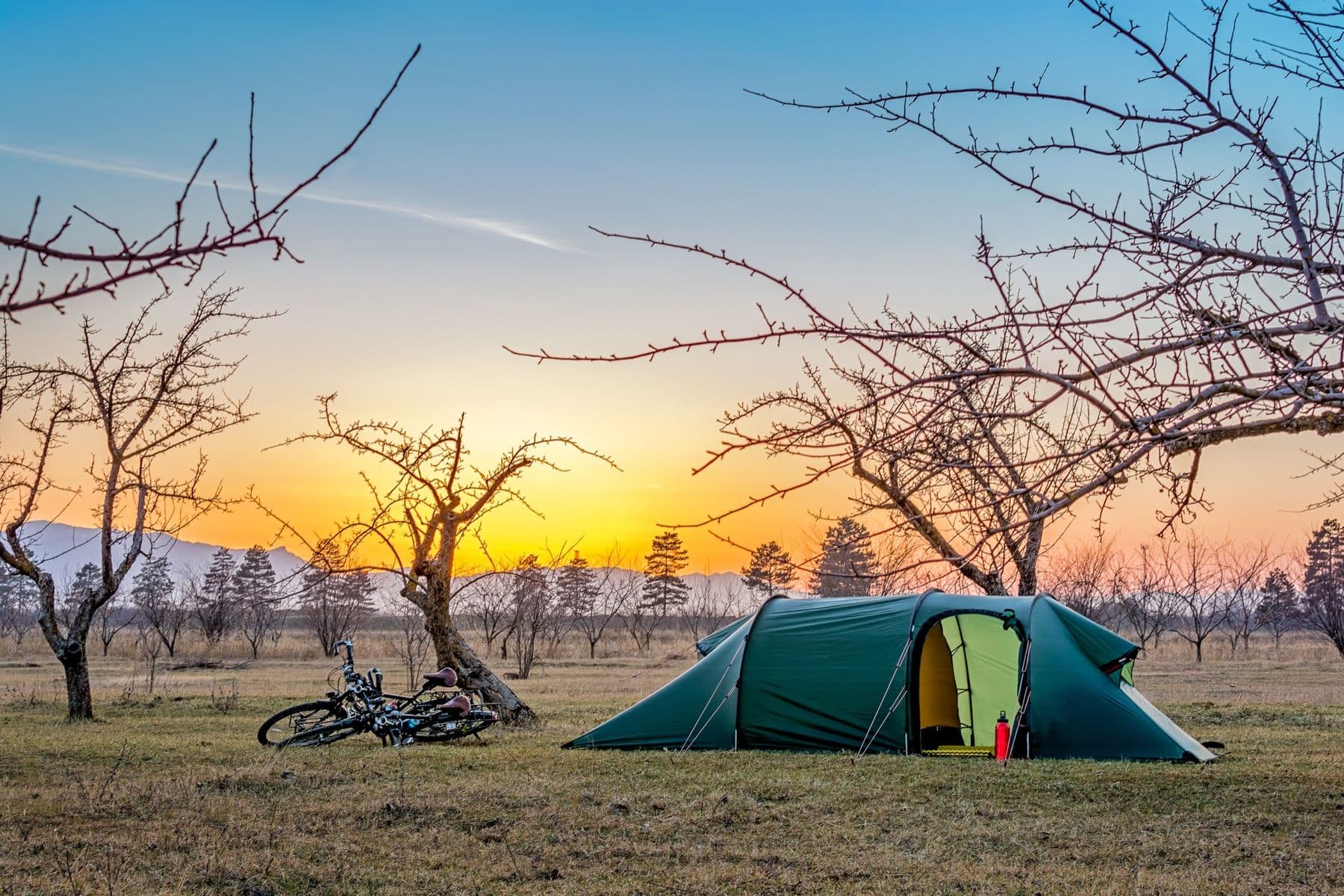 My tent and loaded bicycle pitched at golden hour in open, bare winter country
