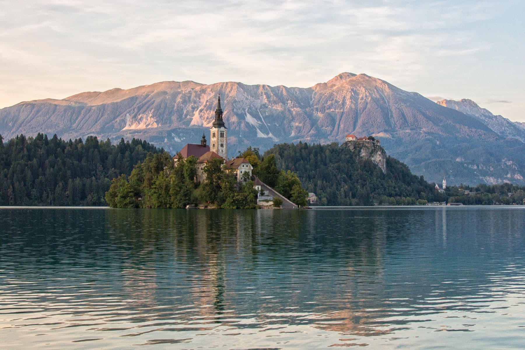 The island church on Lake Bled, a castle and mountains behind at golden hour