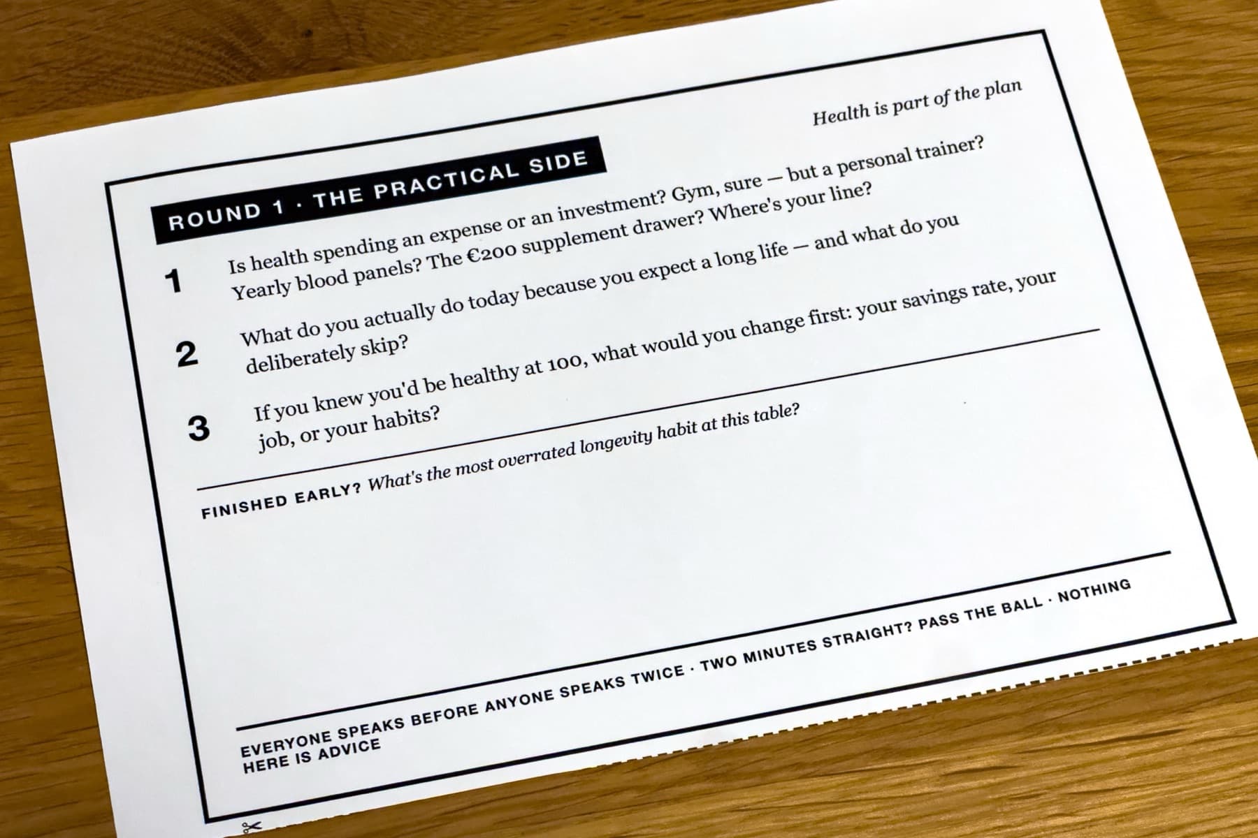 A printed question card headed 'Round 1 · The practical side' resting on a wooden table
